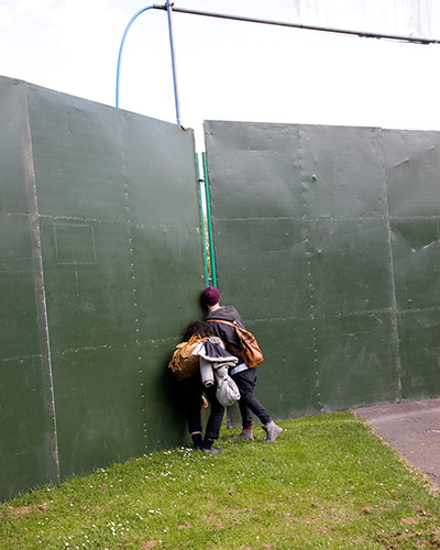 Big Picture - Peeking: woman with child looking through gap in hoarding