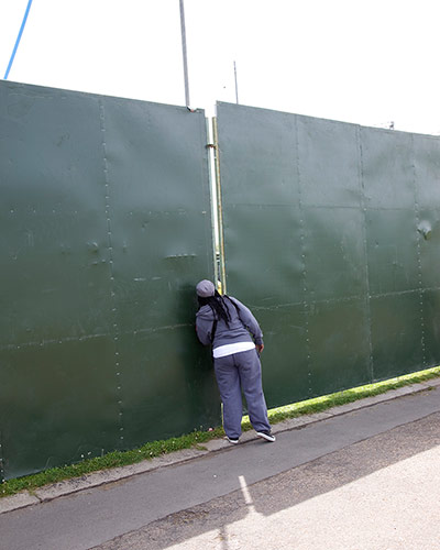 Big Picture - Peeking: woman looking through gap in hoardings