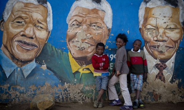 Children pose for a photograph in front of a mural of Nelson Mandela in Soweto. As messages of support pour in from around the world, Mandela remains in a critical condition in hospital.