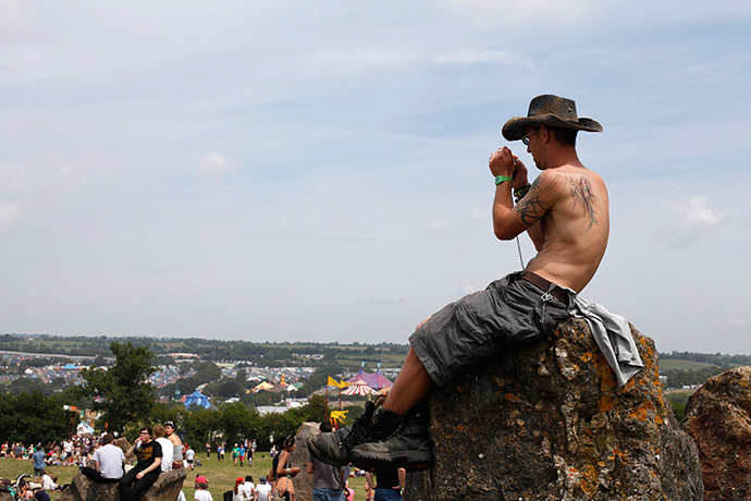 Glastonbury: A festival goer sits on top of one of the standing stones in the stone circ
