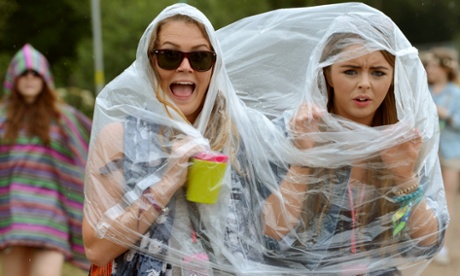 Festival goers sharing a poncho in the rain during the second day of the Glastonbury Festival.