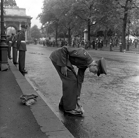 Queen's coronation 1953: A Royal Air Force man stoops as he gives his shoes a quick clean 