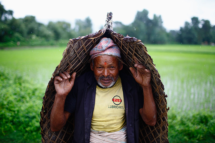 weekend in pictures: Bhaktapur, Nepal: A farmer covers himself from the rain during Asar Pandra 