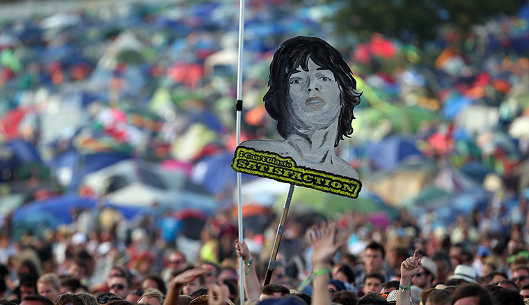weekend in pictures: Glastonbury, UK: Music fans hold up a poster of Mick Jagger at the Glastonb