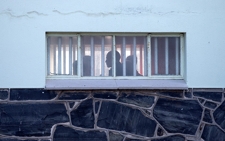 Obama Robben Island: President Back Obama in silhouette walks by bar covered windows