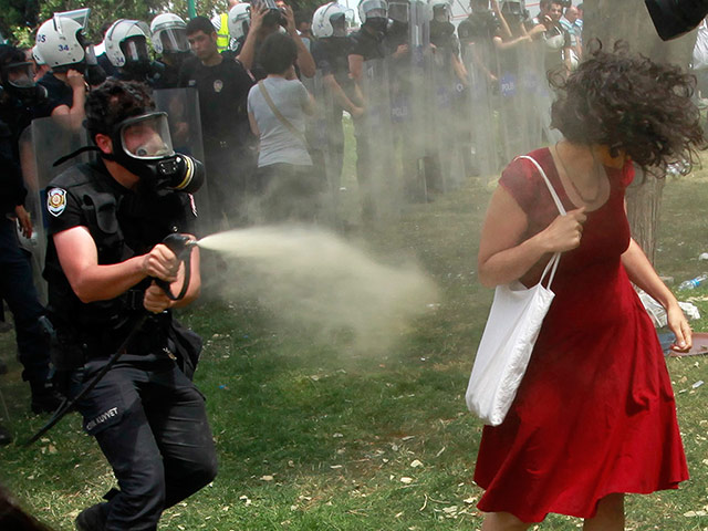 Turkey riots: A Turkish riot policeman uses tear gas against