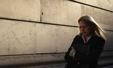 A woman in a suit, business attire, possibly a businessman, walks in the City of London. 