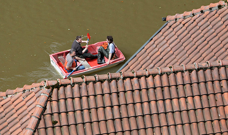 flooding: Local residents paddle their boat past flooded houses in Hrensko