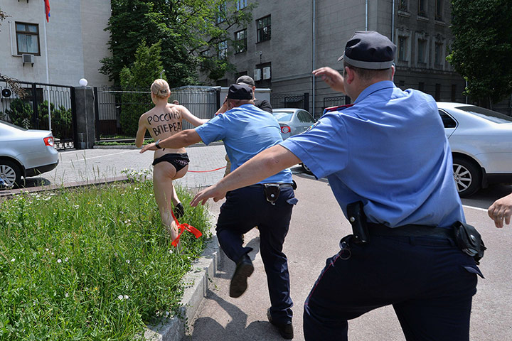 20 Photos: A member of Femen runs away from policemen in Kiev
