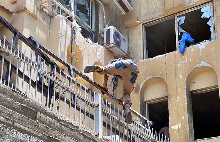 Egypt update: An Egyptian man jumps on the wall at the Muslim Brotherhood's national head