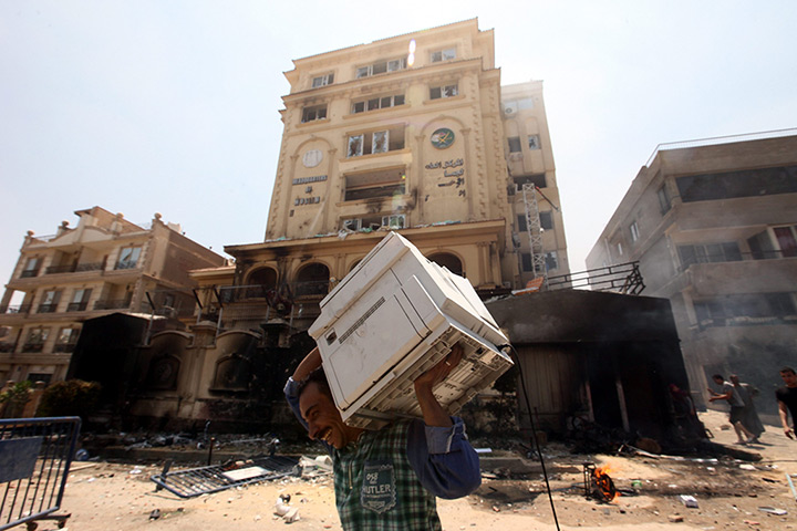 Egypt update: An Egyptian man carries items looted from the headquarters of the Muslim Br