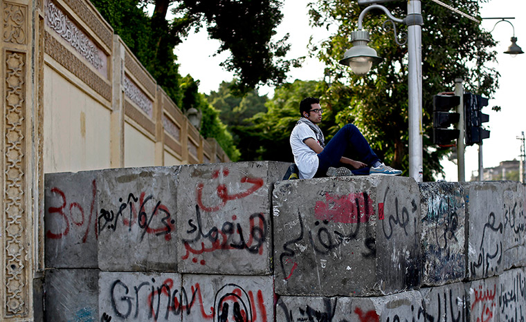 Egypt update: An opponent of Egypt's Islamist President Mohammed Morsi sits on cement bar