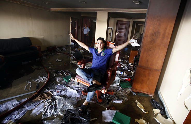Egypt update: A looter sits on a chair at the Muslim Brotherhood's headquarters after it 