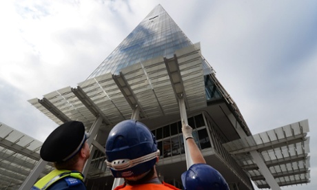 A policeman and emergency services personnel watch as Greenpeace women activists climb Europe's tallest building, the Shard in London.
