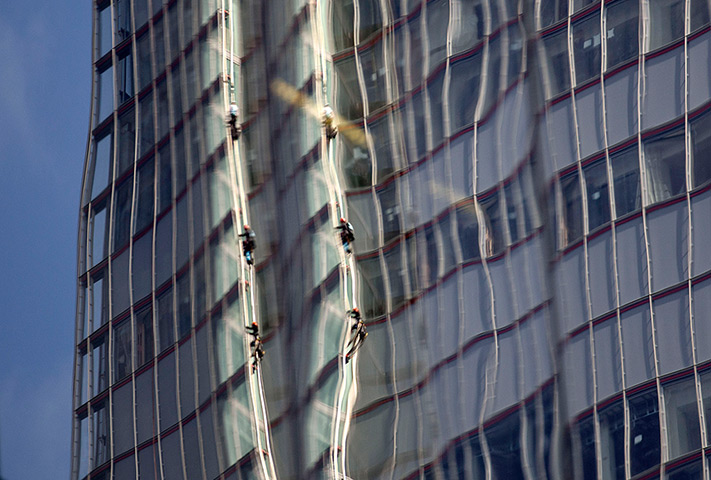 Greenpeace Shard: Reflected in a nearby building, Greenpeace protesters climb up The Shard