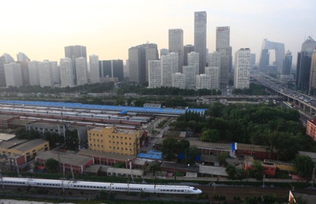 A China Railway High-speed (CRH) Harmony bullet train (bottom) drives past Beijing's central business district, July 11, 2013.