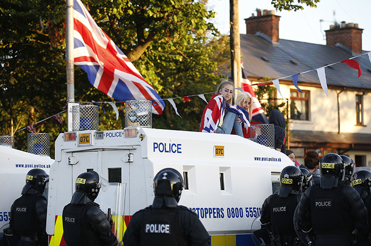 Belfast unrest: Loyalist protesters sit on top of a police armoured vehicle. The protesters