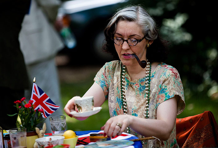 Chap Olympiad: A woman smokes a pipe whilst preparing her tea.