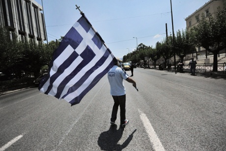 A municipal police officer holds a Greek flag during a protest in front of the Parliament in Athens, Greece, 15 July 2013