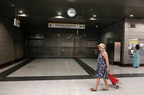 A commuter walks by a closed train station in a northern Athens suburb July 16, 2013