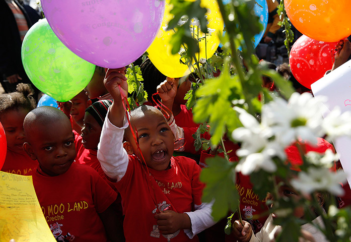 Mandela's birthday: Children hold balloons and flowers as they gather outside the hospital in P
