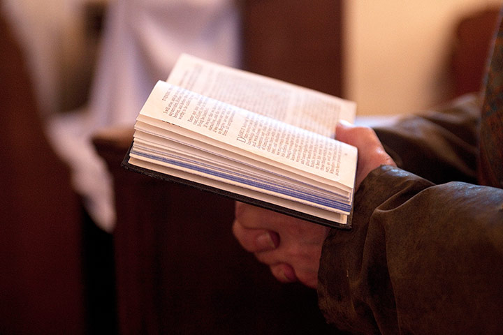 CofE: A member of the congregation follows the service