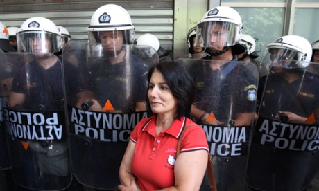 A protesting high-school teacher stands in front of riot police officers outside the Finance Ministry, in central Athens, Monday, July 22, 2013.
