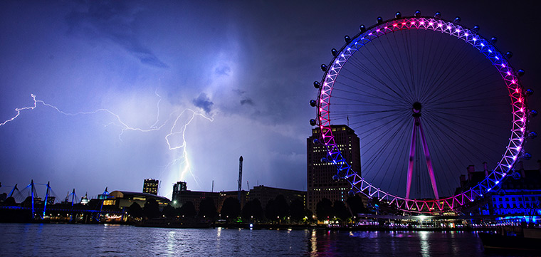 Royal blue: Lightning strikes behind The London Eye in central London which is coloured