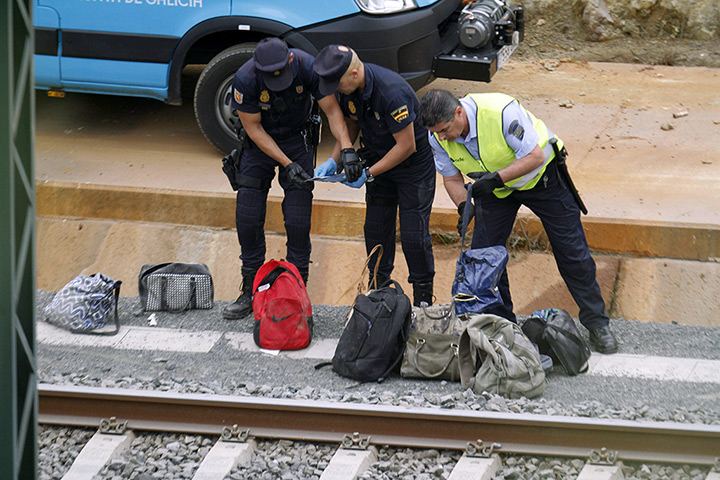 Spanish train update: Policemen sort personal items at the scene of a train accident