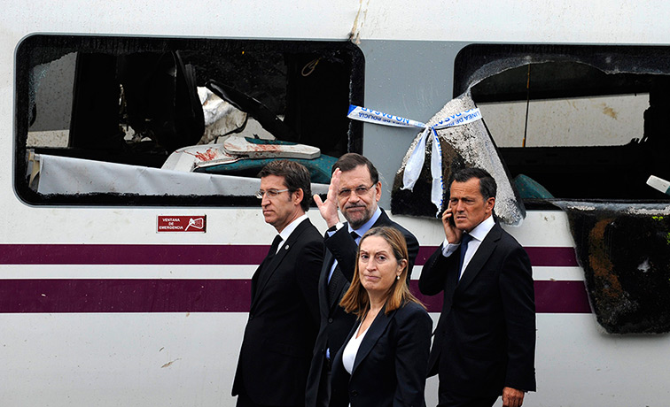 Spanish train update: Spain's Prime Minister Mariano Rajoy waves as he walks with Development Min