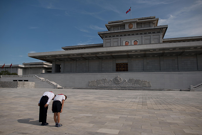 North Korea 60th: Two school children bow before the portraits of late North Korean leaders K