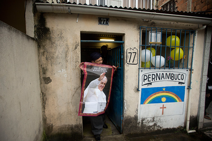 Pope in Brazil: A woman poses with a poster of Pope Francis outside her home before the Pop