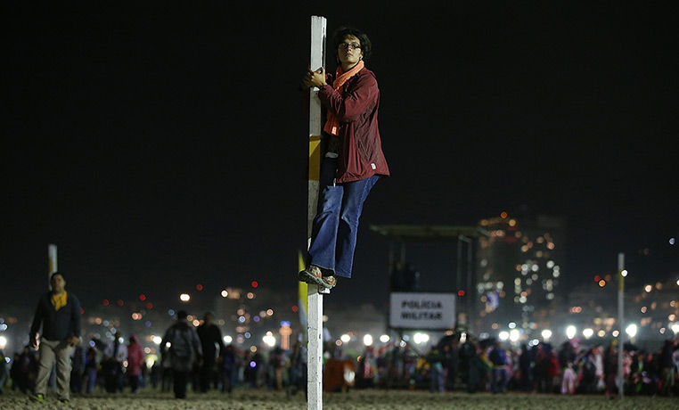 Pope Brazil updated: A woman watches from a pole as Pope Francis celebrates Mass