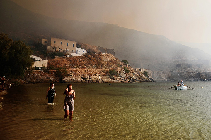 Wildfires Greek islands: Tourists wade in the sea as a wildfire approaches Megalo Livadi 