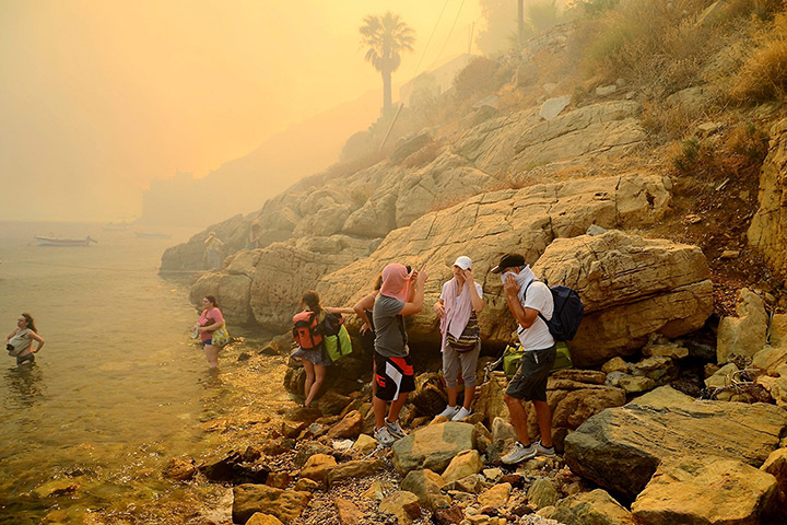 Wildfires Greek islands: Tourists and inhabitants try to escape the smoke on the beach at Megalo Liv