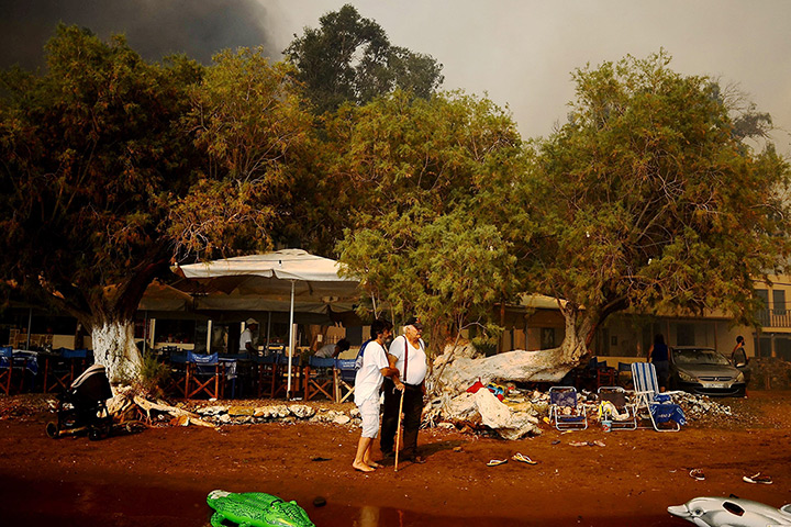 Wildfires Greek islands: An elderly man is helped as a wildfire approaches