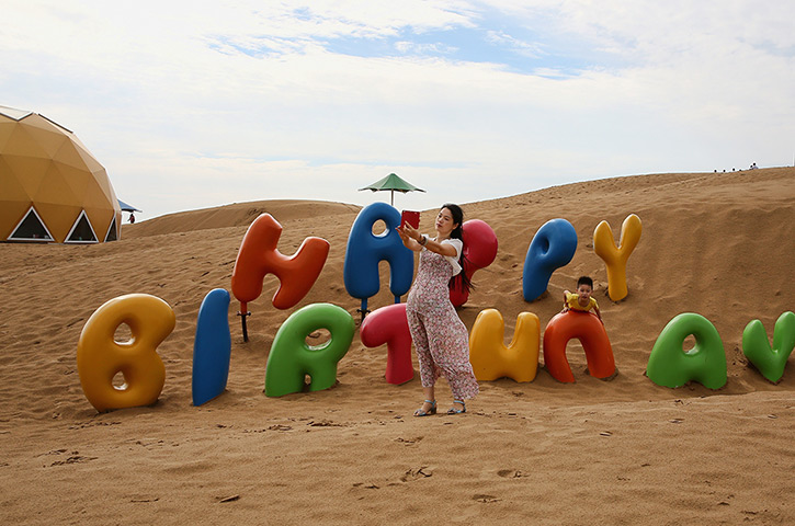 Sounding Sand Desert: A woman takes photos with smart phone