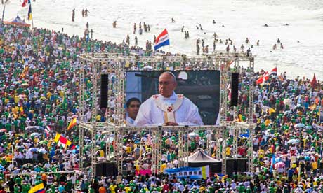 Pilgrims watch Pope Francis on a video screen as he celebrates mass on Copacabana Beach
