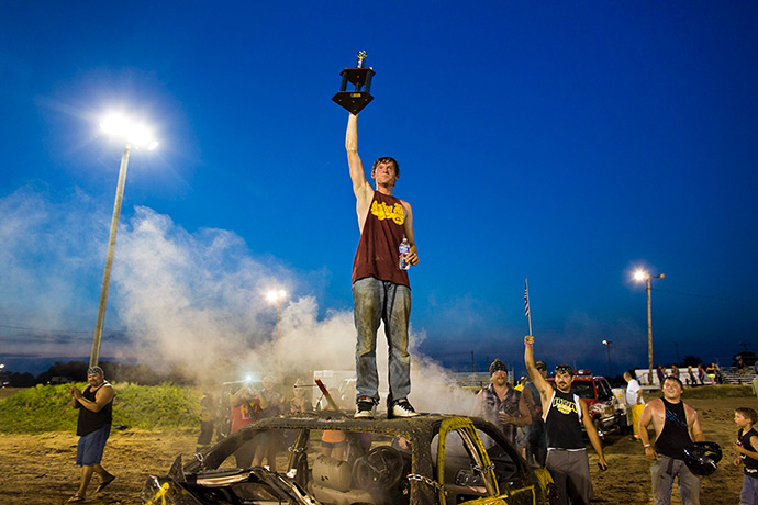 Iowa County Fair: Kyle Barh stands on the hood of his car and waves his first-place trophy af