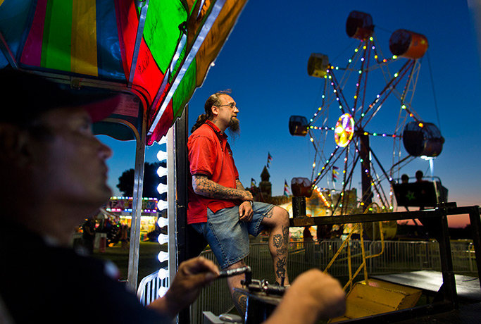 Iowa County Fair: Part-time carnival worker Eric Helfter watches children on a ride called th