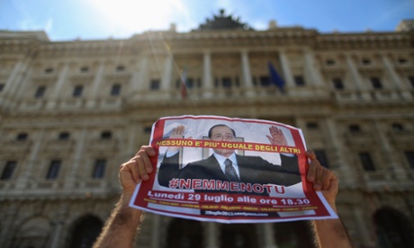 A man holds up a picture of former Italian Prime Minister Silvio Berlusconi as he protests in front of Italy's supreme court building in Rome July 30, 2013.