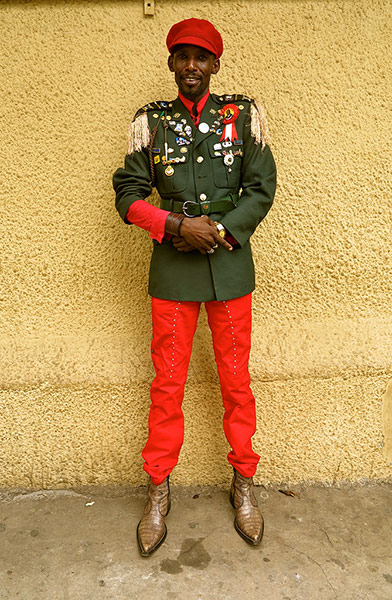 Big Picture - Africa: Man dressed in red trousers and army wear in front of yellow wall