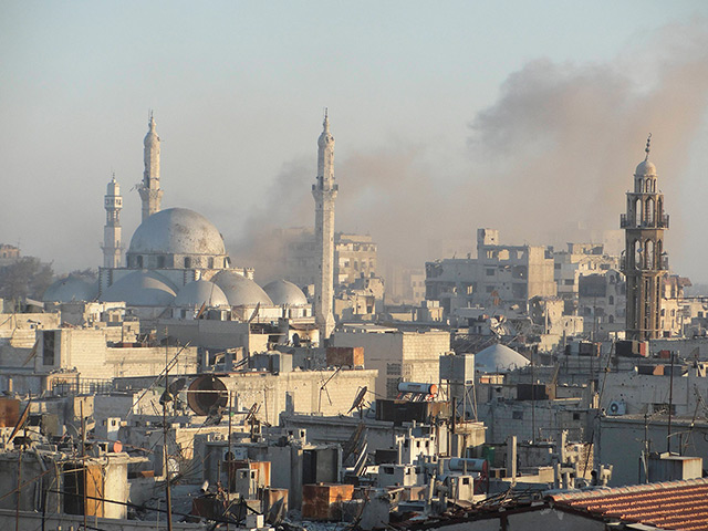 Homs destruction: Smoke rises near Khalid bin al Walid Mosque in the Khalidiyah district of H