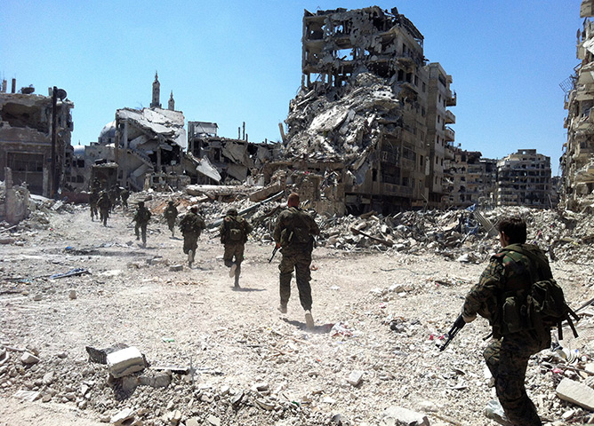 Homs destruction: Syrian government forces patrol in the Khalidiyah neighbourhood. Government