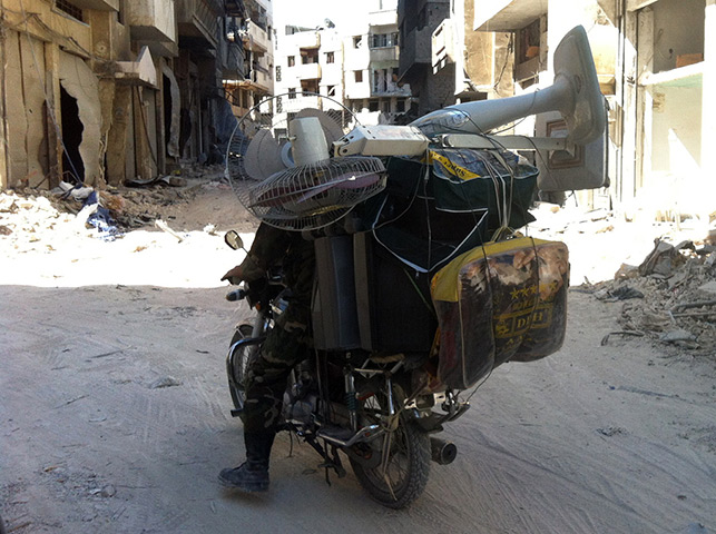 Homs destruction: A Syrian carries personal belongings on his motorbike in Khalidiyah