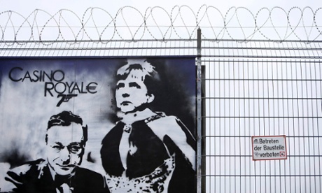 A graffiti depicting European Central Bank (ECB) President Mario Draghi and German Chancellor Angela Merkel is seen outside a fence surrounding the construction site for the new ECB headquarters in Frankfurt, July 3, 2013.