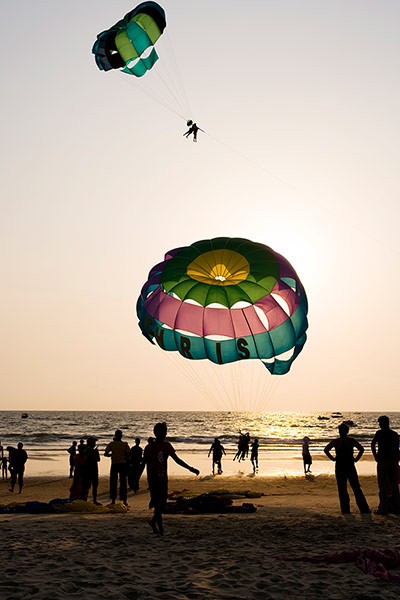 TUI: Goa: TUI: Paragliders on beach at sunset.