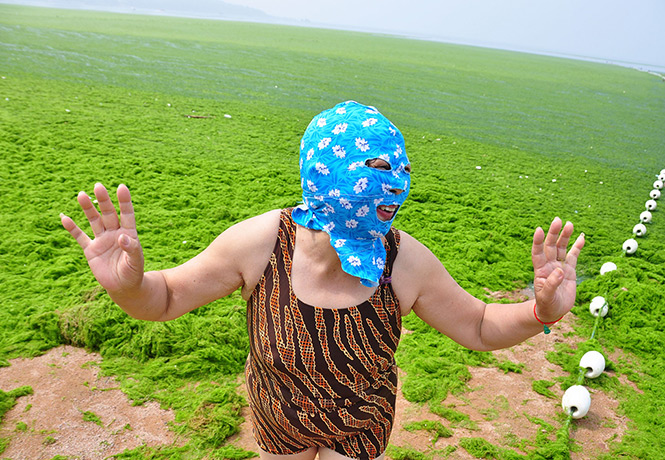 China algae: A woman wearing mask plays at a beach