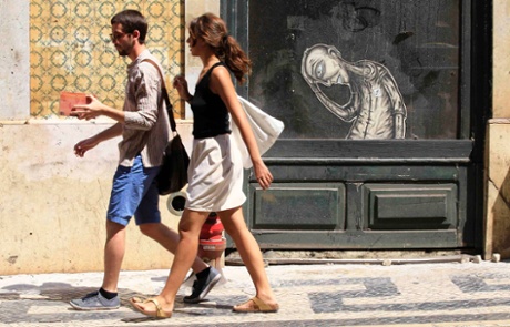 A couple walks past a closed shop in downtown Lisbon July 5, 2013