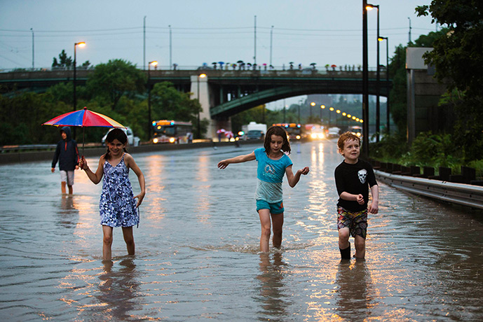 Canada floods: Children walk on the Don Valley Parkwayduring a heavy rainstorm